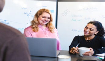Three colleagues having a discussion around a laptop. Source: Tech.co