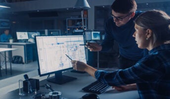 A person shows a colleague something in a project management app on a computer.
