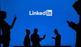 Silhouettes of people on screens in front of LinkedIn logo