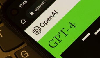 OpenAI and GPT-4 logos open on mobile screen on top of laptop keyboard