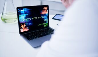 Man is white coat looking at a cyberattack on laptop