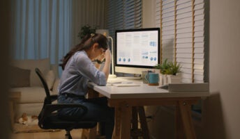 Young woman sitting head in hands at home office desk