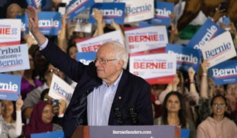 Bernie Sanders waving at a rally with supporters