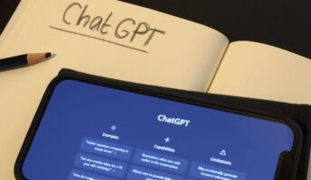 Smart phone with the online AI chat program ChatGPT. Notebook and pencil, ready to take notes for schoolwor