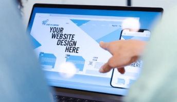 Two people gathered round a laptop with a website builder open on the screen. Source: Tech.co